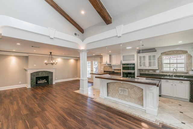kitchen featuring a sink, decorative columns, stainless steel appliances, dark countertops, and a tile fireplace
