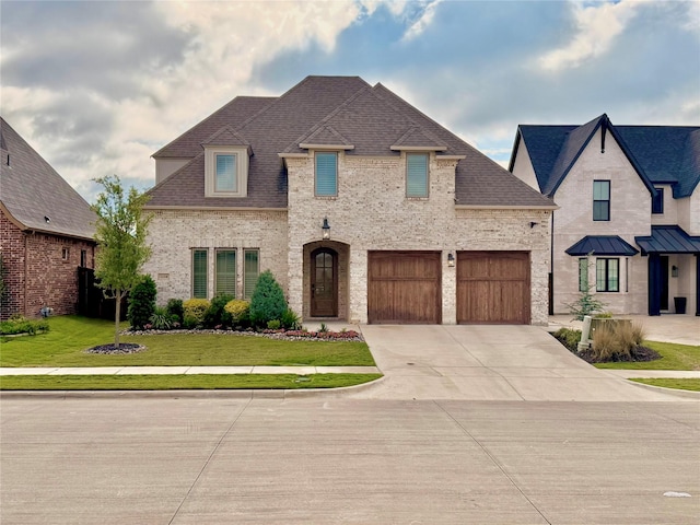 french country style house featuring concrete driveway, a front lawn, brick siding, and a shingled roof
