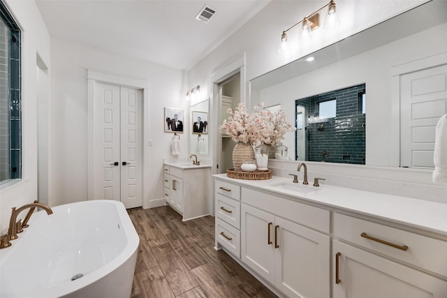 2218 Somercrest Pl, Midlothian, TX 76065 - bathroom featuring two vanities, a freestanding bath, wood finished floors, and tiled shower