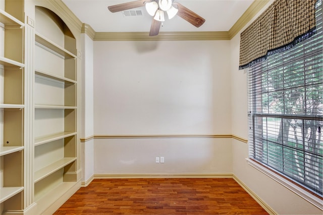 spare room featuring ceiling fan, wood finished floors, crown molding, and baseboards