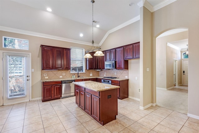 kitchen featuring stainless steel appliances, a sink, backsplash, arched walkways, and lofted ceiling