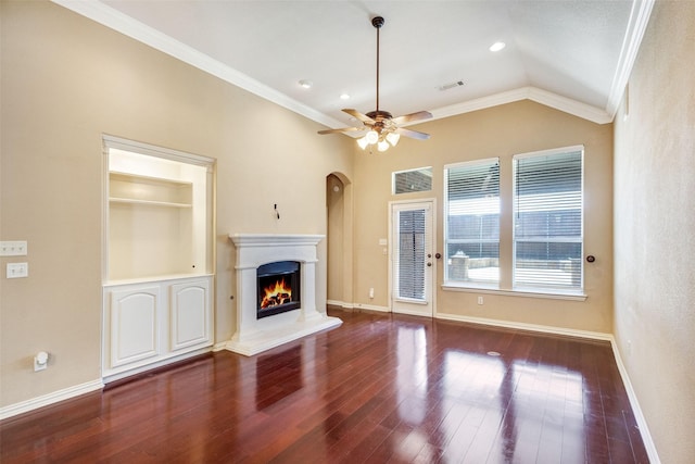 unfurnished living room featuring ornamental molding, a warm lit fireplace, vaulted ceiling, a ceiling fan, and wood finished floors