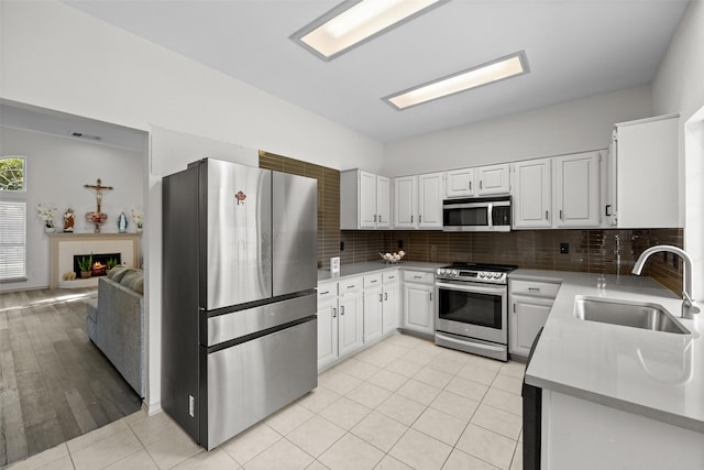 2410 Hedgeway Cir, Garland, TX 75044 - kitchen featuring stainless steel appliances, a sink, tasteful backsplash, light countertops, and white cabinetry