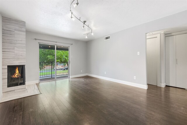 unfurnished living room with baseboards, a fireplace, a textured ceiling, and wood finished floors