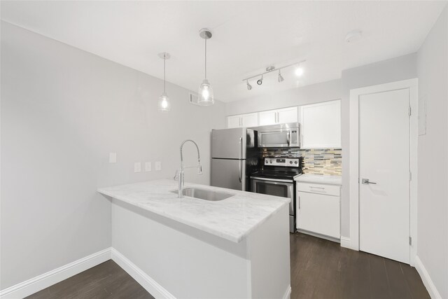 kitchen with appliances with stainless steel finishes, a sink, a peninsula, dark wood-type flooring, and white cabinetry