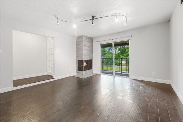 unfurnished living room featuring a multi sided fireplace, wood finished floors, and baseboards