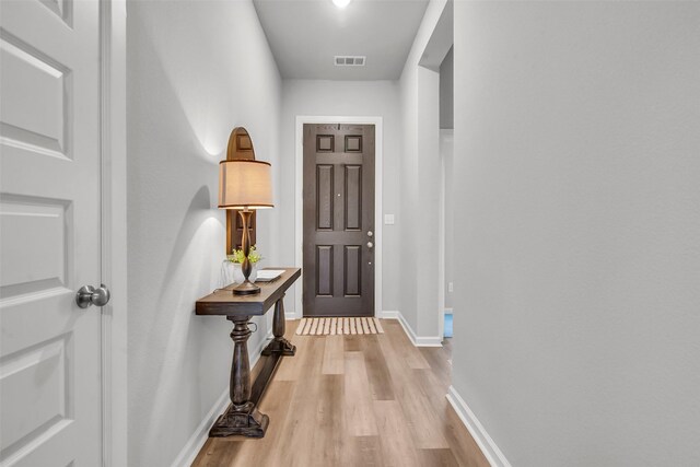 doorway to outside featuring light wood finished floors and baseboards