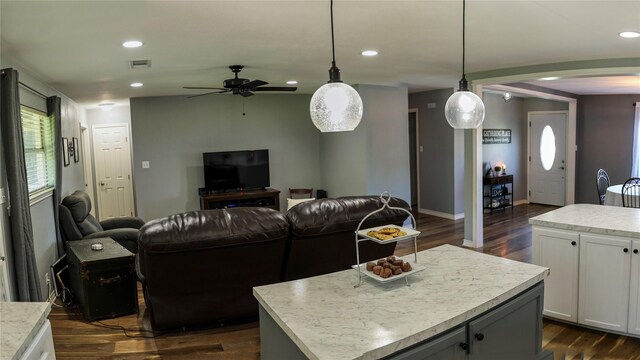 kitchen with open floor plan, a center island, a ceiling fan, dark wood-style flooring, and arched walkways