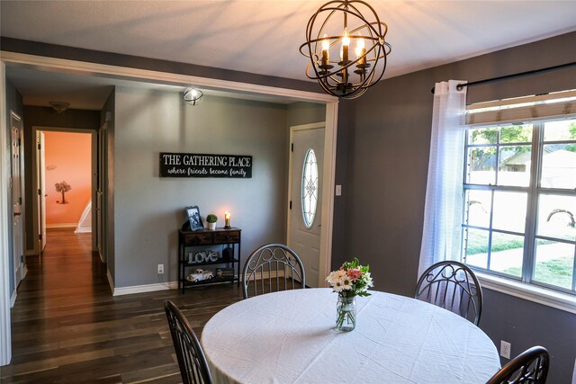dining room featuring dark wood-type flooring, a chandelier, plenty of natural light, and baseboards