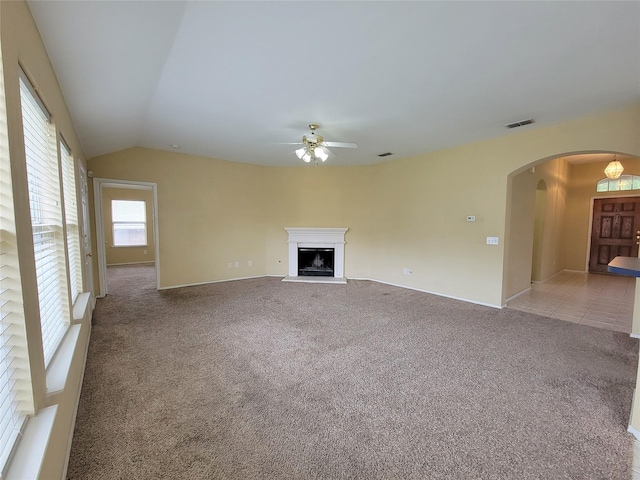 1006 Redwood Trl, Rockwall, TX 75087 - unfurnished living room featuring ceiling fan, arched walkways, carpet, a fireplace with raised hearth, and lofted ceiling