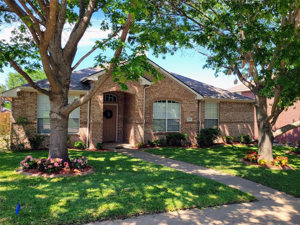 1006 Redwood Trl, Rockwall, TX 75087 - view of front facade with brick siding, a front yard, and roof with shingles