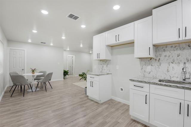 3030 Utah Ave, Dallas, TX 75216 - kitchen with a sink, light stone counters, white cabinets, baseboards, and recessed lighting