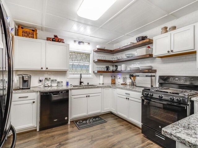 kitchen featuring black appliances, decorative backsplash, a sink, and white cabinetry