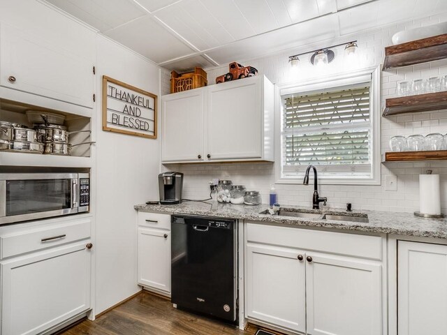 kitchen with black dishwasher, stainless steel microwave, a sink, backsplash, and white cabinets