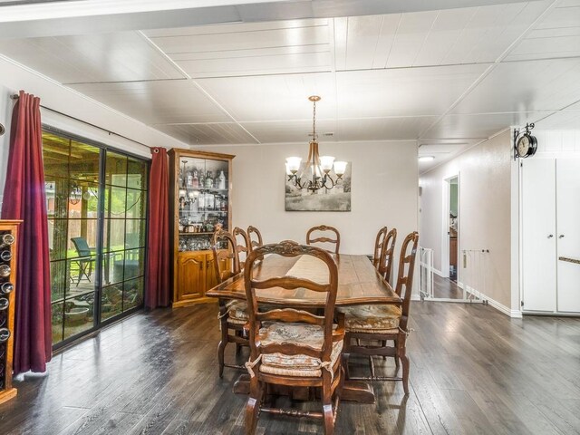 dining area with dark wood-style flooring, a chandelier, and baseboards