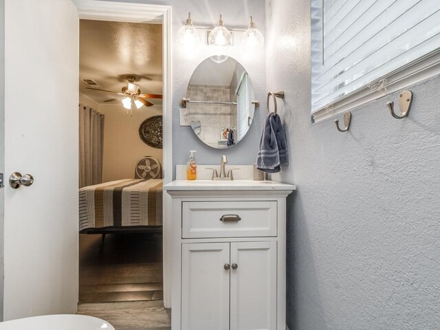 bathroom featuring vanity, ceiling fan, wood finished floors, and a textured wall
