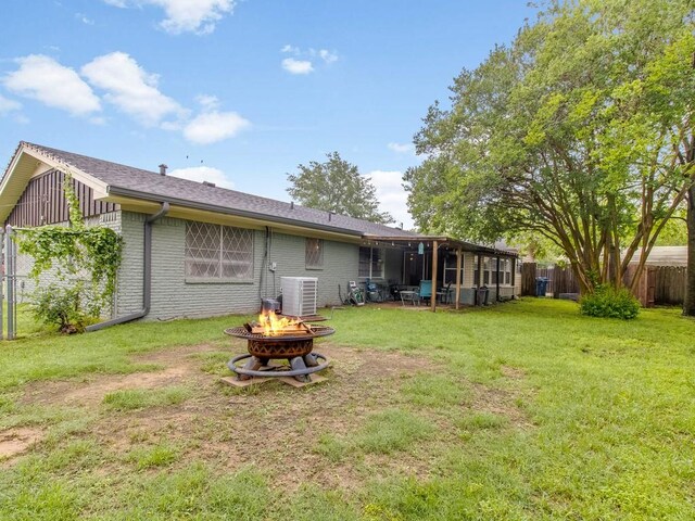 rear view of property featuring an outdoor fire pit, central air condition unit, brick siding, a sunroom, and roof with shingles