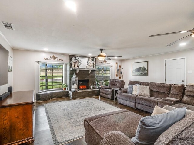 living room featuring ceiling fan, dark wood finished floors, and a lit fireplace