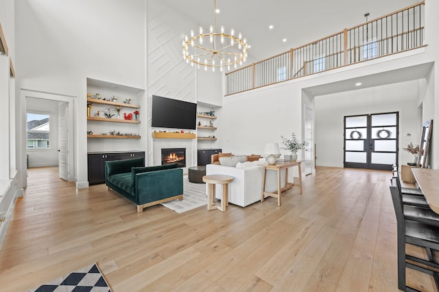 1914 Mann Pkwy, Celina, TX 75009 - living room featuring a high ceiling, light wood finished floors, a large fireplace, a chandelier, and french doors