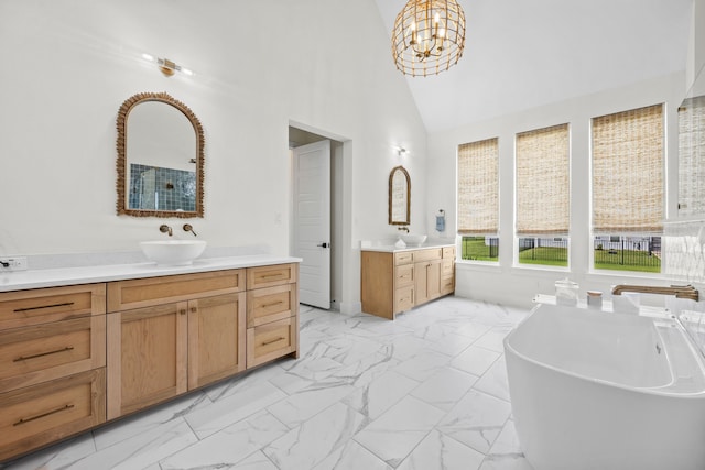 1914 Mann Pkwy, Celina, TX 75009 - full bathroom with marble look tiles, two vanities, a freestanding tub, a chandelier, and high vaulted ceiling