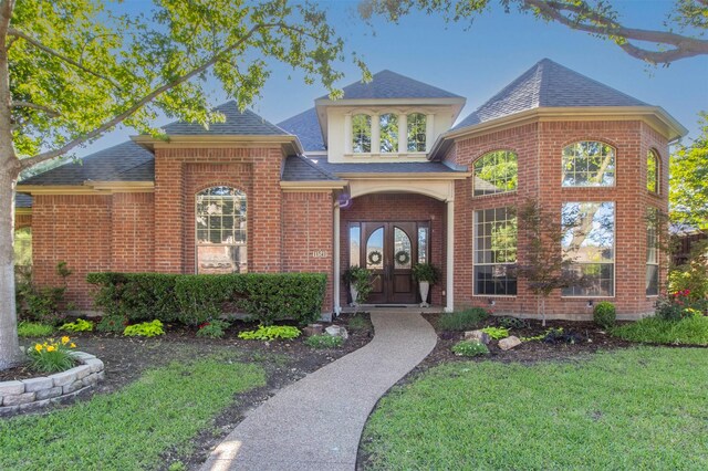 view of front of home with roof with shingles, brick siding, and a front lawn