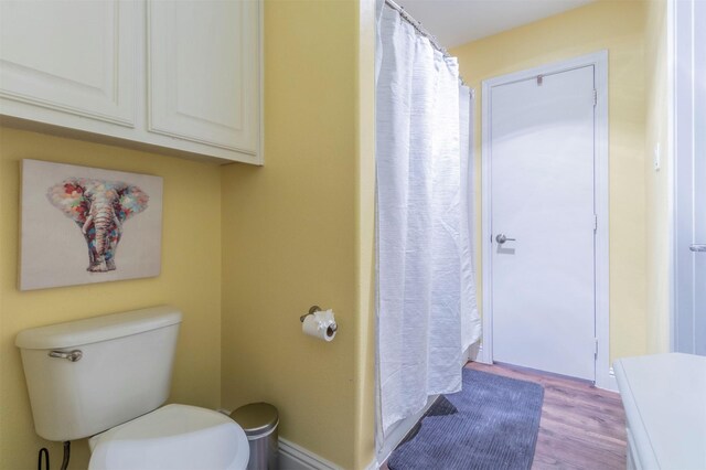 full bath featuring wood finished floors, toilet, and curtained shower