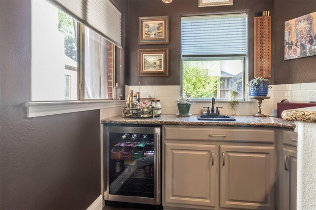 indoor bar featuring wine cooler, decorative backsplash, and a textured wall