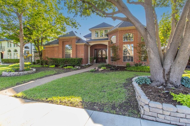 traditional-style home with brick siding and a front lawn
