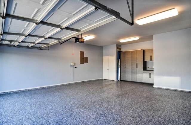 garage featuring a garage door opener, electric panel, and baseboards