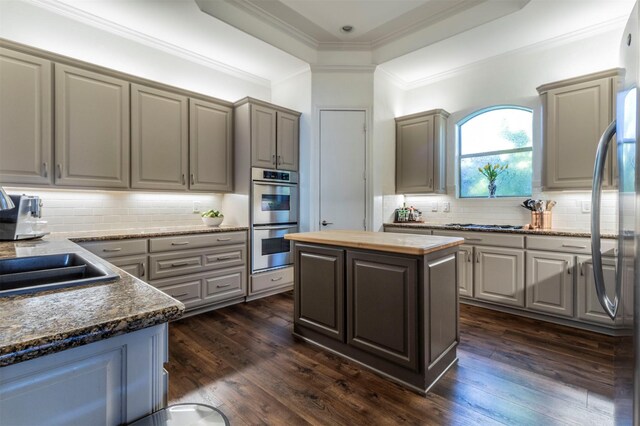 kitchen with stainless steel appliances, gray cabinets, backsplash, dark wood-style floors, and ornamental molding