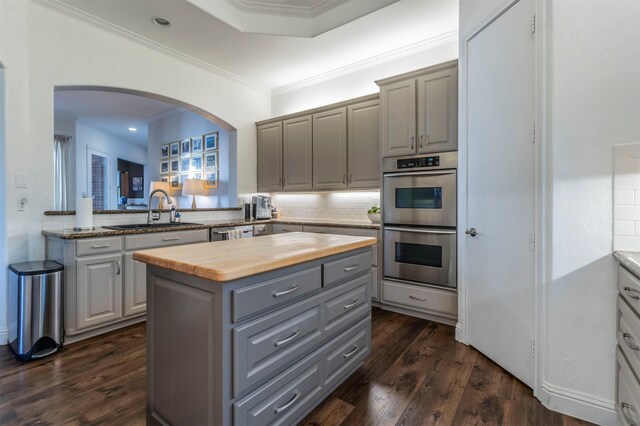 kitchen with a sink, butcher block countertops, gray cabinetry, appliances with stainless steel finishes, and a kitchen island