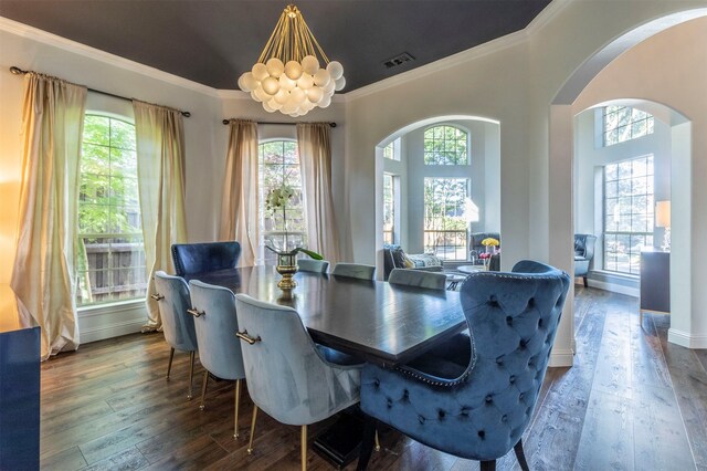dining area featuring arched walkways, ornamental molding, and dark wood-type flooring