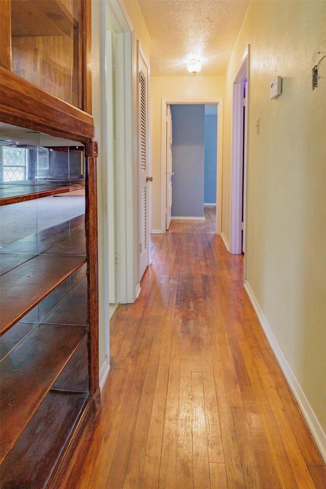 1809 Stevens St, Bridgeport, TX 76426 - hall with wood-type flooring, a textured ceiling, and baseboards