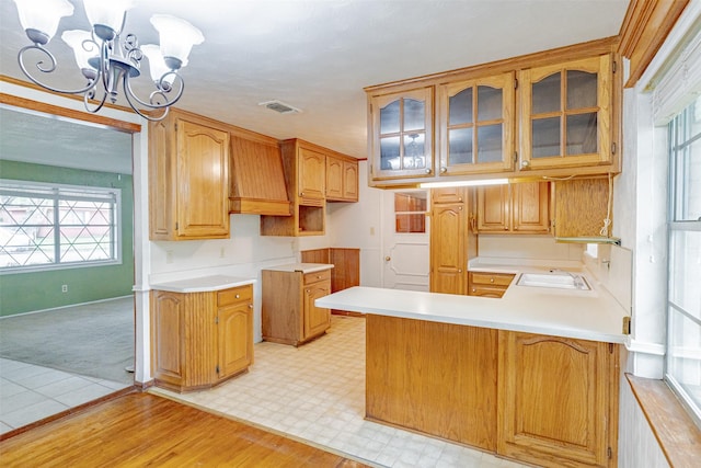 1809 Stevens St, Bridgeport, TX 76426 - kitchen featuring a chandelier, glass insert cabinets, a peninsula, light countertops, and light carpet