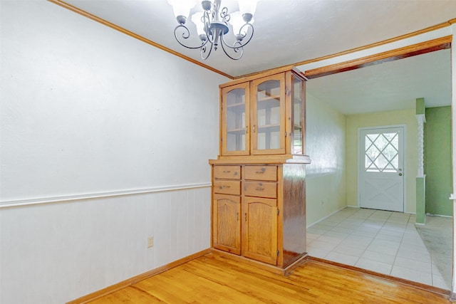1809 Stevens St, Bridgeport, TX 76426 - foyer entrance with a chandelier, light wood-style flooring, crown molding, wainscoting, and baseboards
