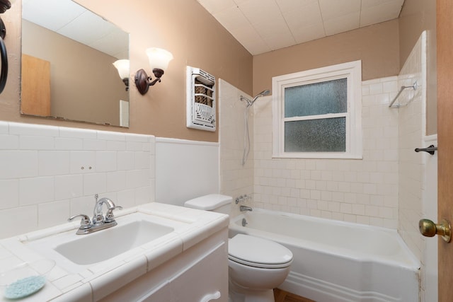 bathroom featuring shower / bath combination, toilet, vanity, and wainscoting