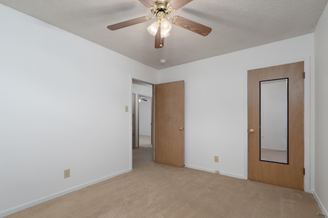 carpeted empty room featuring a ceiling fan, baseboards, and a textured ceiling