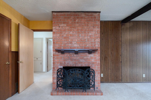 carpeted living area with wood walls, a textured ceiling, beam ceiling, and a fireplace