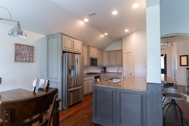 2974 Sparks Dr, Frisco, TX 75036 - kitchen with appliances with stainless steel finishes, a sink, dark wood finished floors, arched walkways, and light stone counters