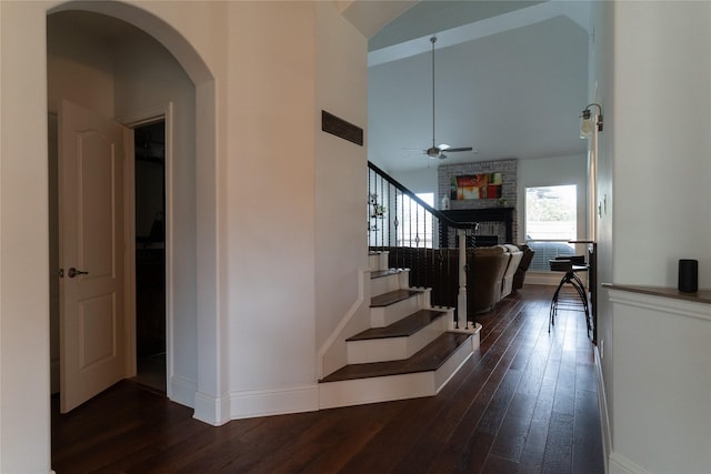 2974 Sparks Dr, Frisco, TX 75036 - staircase featuring a ceiling fan, hardwood / wood-style floors, a fireplace, arched walkways, and baseboards