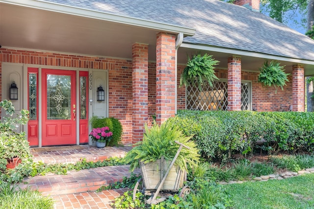 6030 Arden St, Shreveport, LA 71106 - view of exterior entry featuring a shingled roof, brick siding, and a chimney
