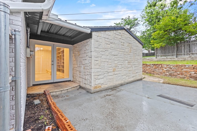 2909 Conejos Dr, Fort Worth, TX 76116 - property entrance with french doors, stone siding, fence, and a patio