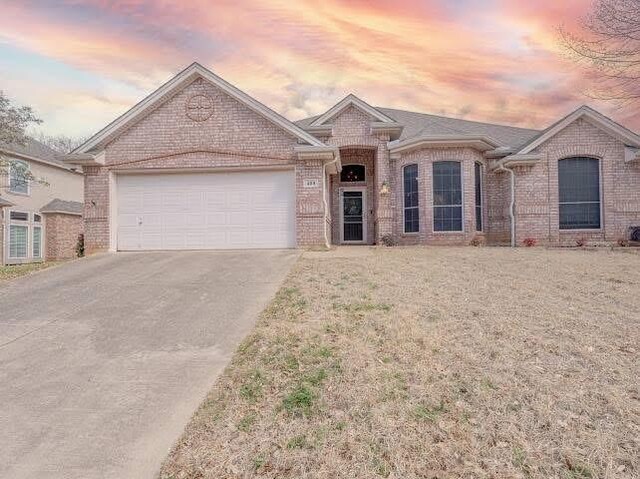 single story home featuring brick siding, driveway, and an attached garage