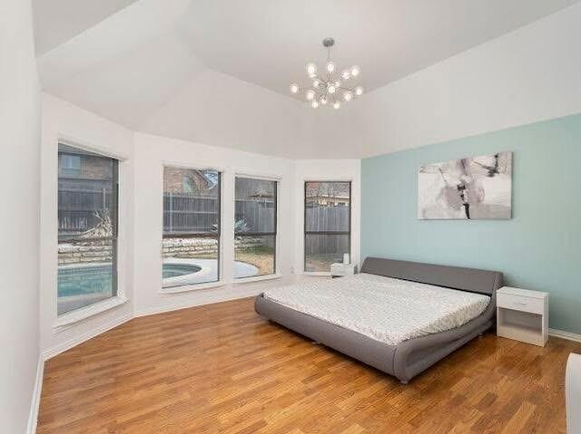 bedroom with a chandelier, wood finished floors, and baseboards