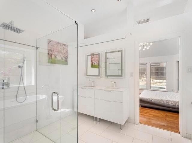 ensuite bathroom featuring a stall shower, vanity, and tile patterned flooring