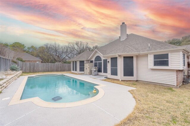 pool at dusk featuring a fenced backyard and a patio area