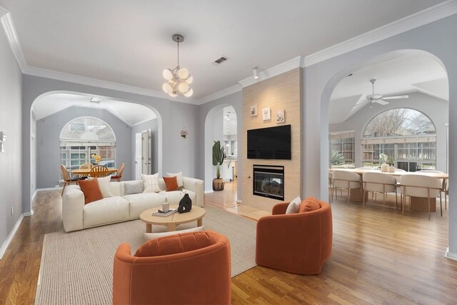 living room with arched walkways, wood finished floors, ceiling fan, vaulted ceiling, and baseboards