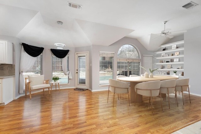 dining space with a ceiling fan, light wood-style flooring, lofted ceiling, and baseboards