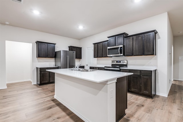 222 Redbarn Ln, Caddo Mills, TX 75135 - kitchen with appliances with stainless steel finishes, a sink, light wood-style flooring, a center island with sink, and light countertops