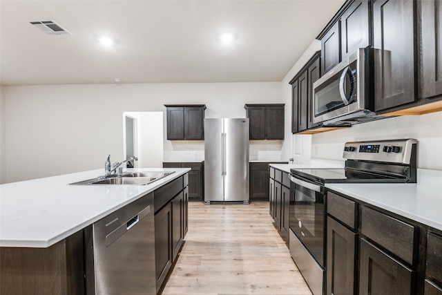222 Redbarn Ln, Caddo Mills, TX 75135 - kitchen with appliances with stainless steel finishes, light wood-style floors, a sink, light countertops, and an island with sink